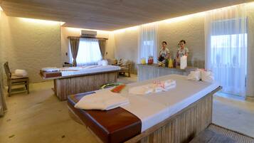 Un cuarto de spa con un banco de madera, una camilla de masaje y un mostrador de recepción con velas y refrigerios.