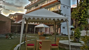 Un espacio de estar al aire libre cubierto con mobiliario de mimbre y un toldo blanco.