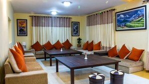 Amplia sala de estar con sofás y una mesa de centro, que presenta un cuadro grande y cortinas.