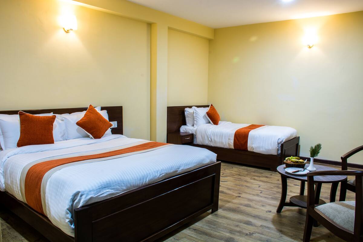 A hotel room with two beds, wooden flooring, and a small table with a plate and a knife.