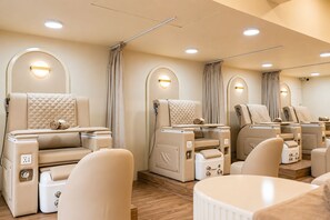 Et spa-værelse med massagestole, et lille bord og et hvidt badekar.