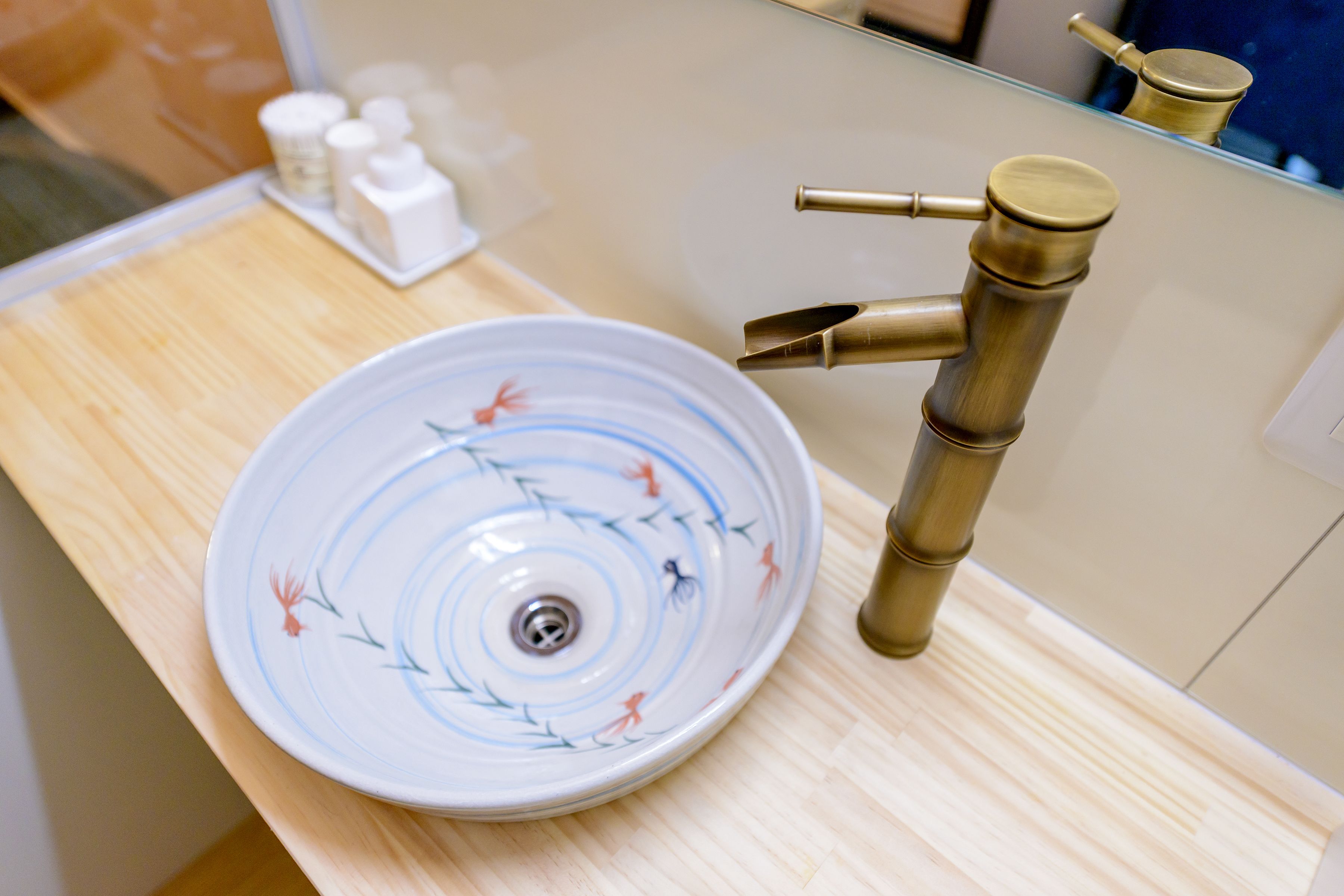 A bathroom sink with a decorative bowl and a bamboo faucet.