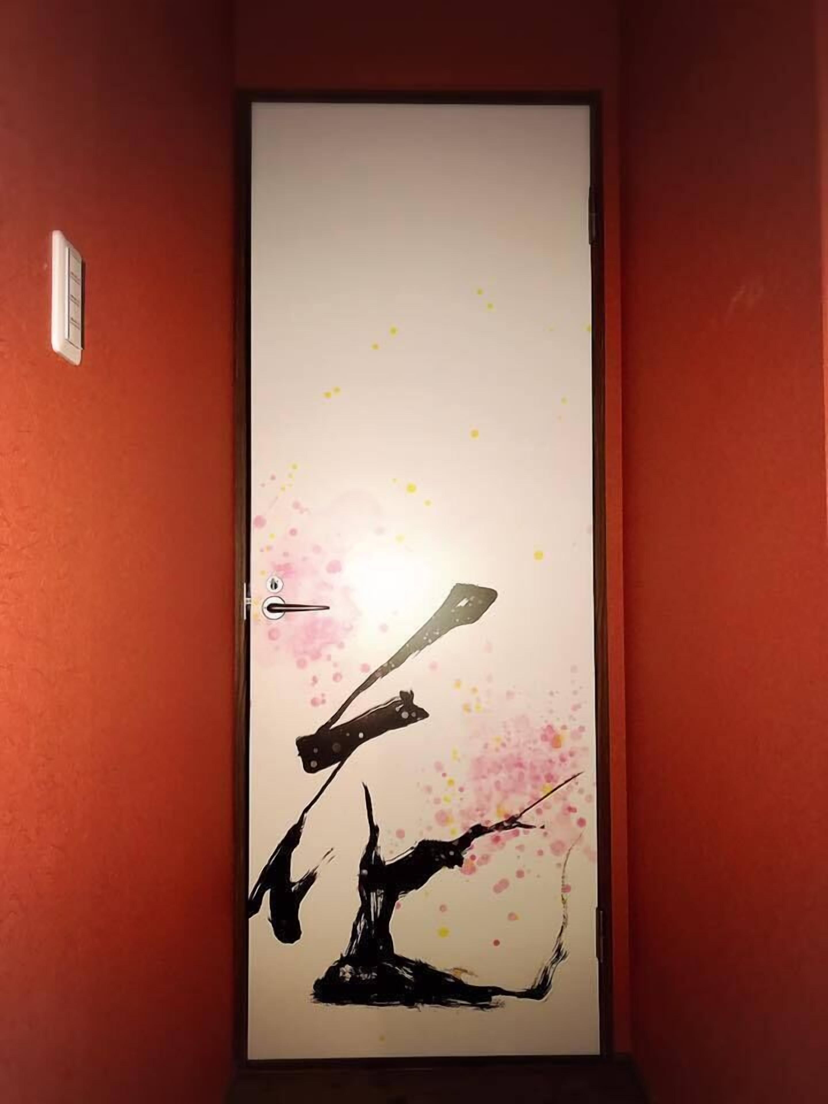 Eine Tür mit einem minimalistischen abstrakten Gemälde, das eine Gitarre und einen Baum zeigt.