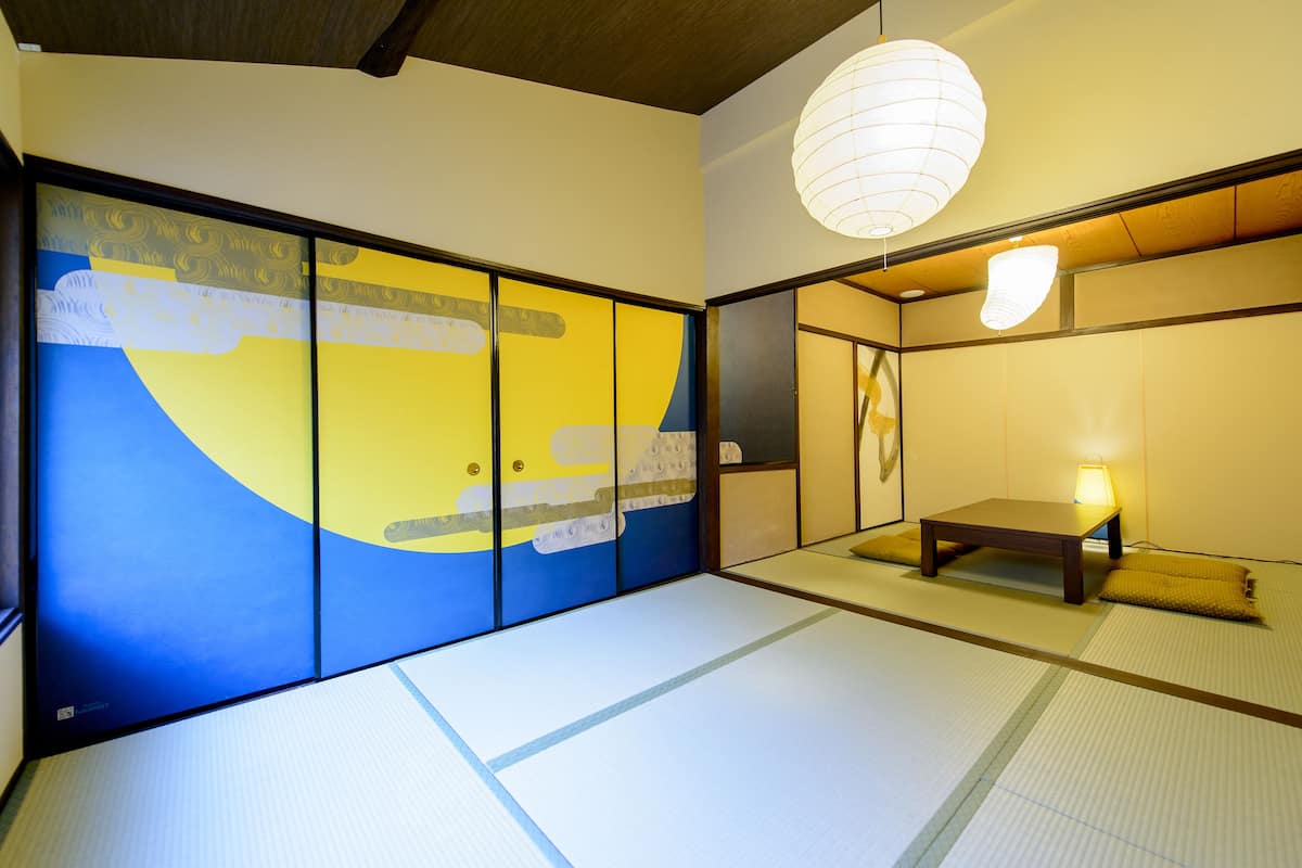 A traditional Japanese room with tatami flooring, a low wooden table, and a hanging paper lantern.
