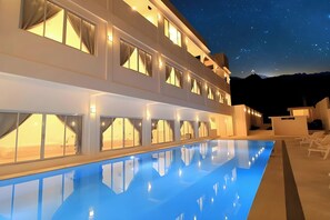 A multi-story hotel with a swimming pool, large windows, and a view of the mountains. - Coron Bluewave Hotel (Coron)