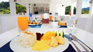 Una mesa de comedor con un plato de arroz, huevos, mangos y un vaso de jugo de naranja.