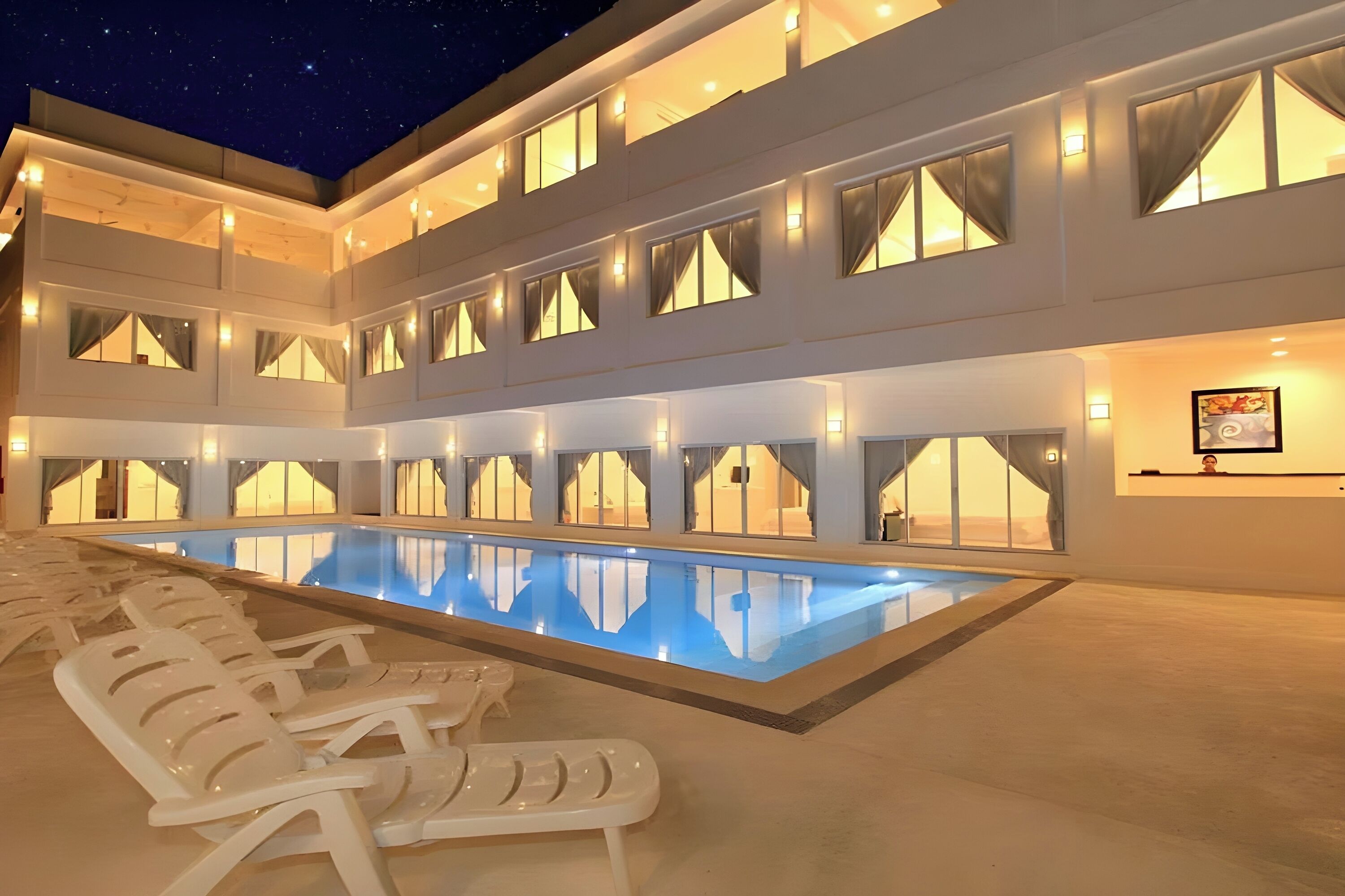 A multi-story hotel with a swimming pool, multiple balconies, and outdoor seating.