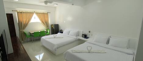 A hotel room with two beds, a desk, a chair, and a small table.