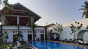 A modern pool area with lounge chairs and a covered seating area. - Hotel Cloud Nine (Negombo)