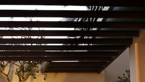 A covered outdoor seating area with a wooden bench and a tree. - Hotel Cloud Nine (Negombo)