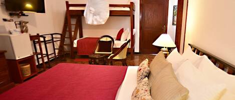 A hotel room with a bed, a desk, a chair, a television, and a door.