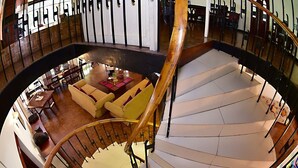 A spacious indoor area with a curved staircase, a seating area with sofas and a coffee table, and a dining area with tables and chairs. - Colombo Villa at Cambridge Place (Colombo)