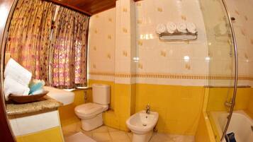 A bathroom with a toilet, bidet, and bathtub.