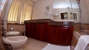 A bathroom with a toilet, bidet, and a large mirror above the sink.
