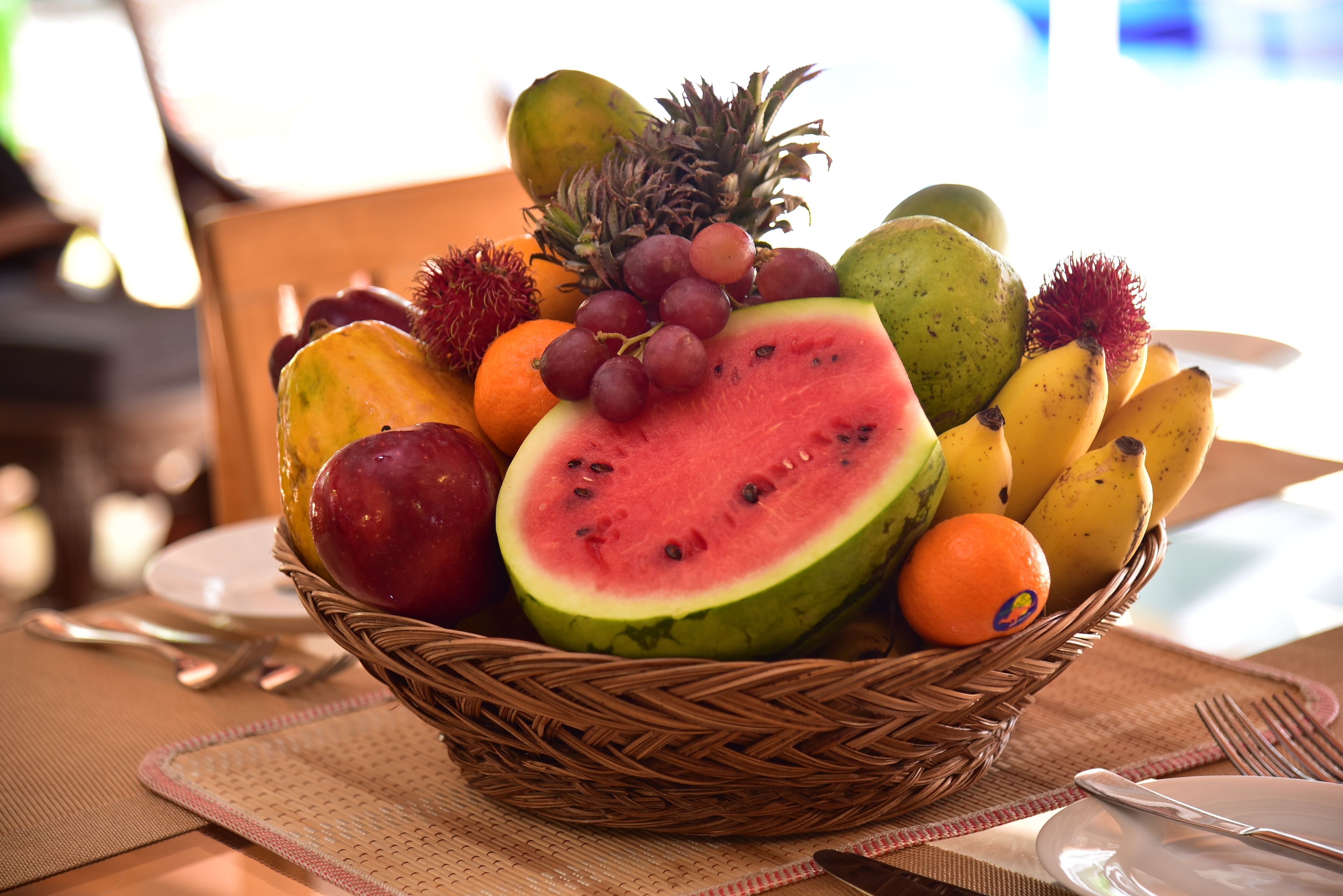 A wicker fruit basket on a table with a placemat.