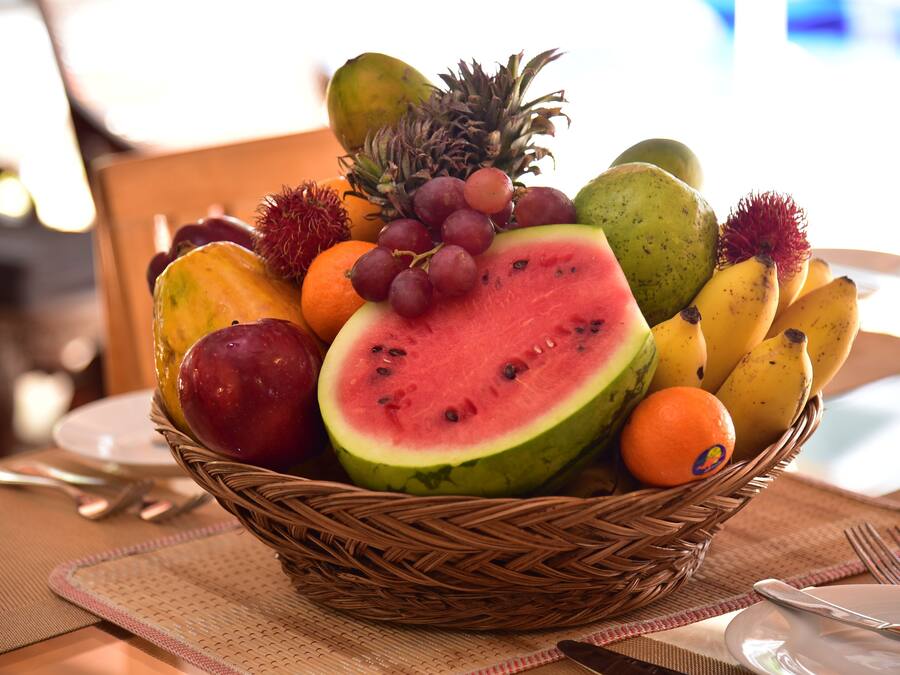 A wicker fruit basket on a table with a placemat.