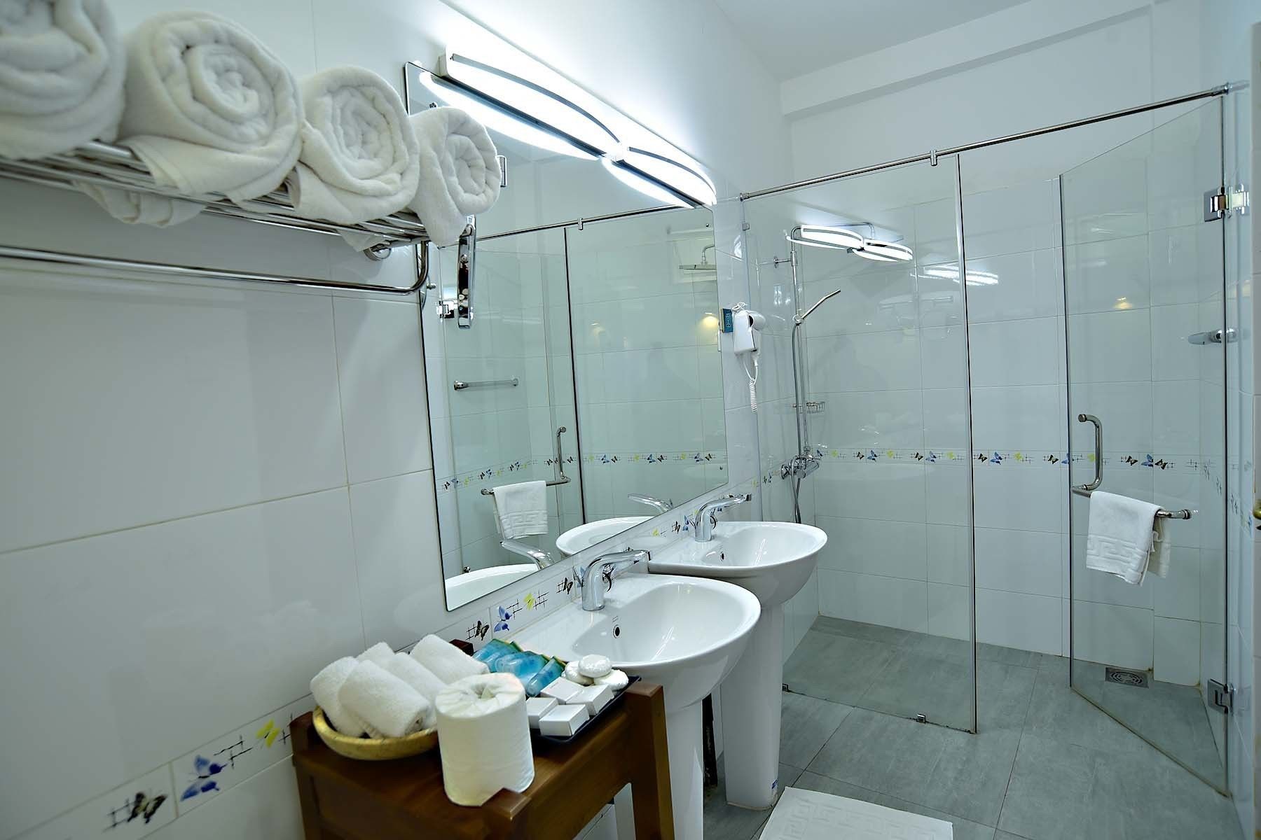 A modern bathroom with a glass shower enclosure, a vanity with a sink, and a mirror.