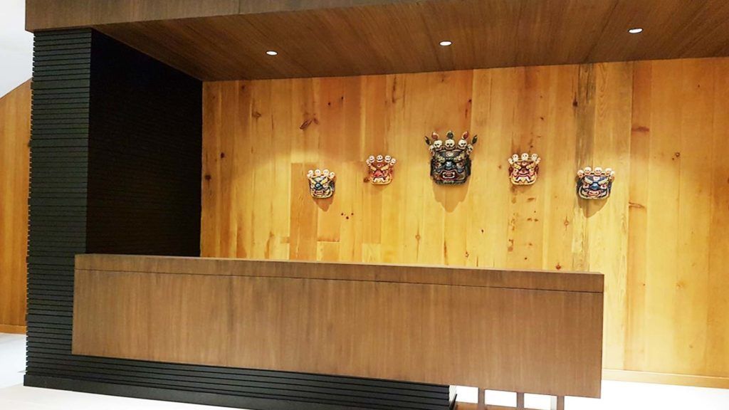 Una reception con un pannello di legno e cinque maschere tradizionali esposte sopra.