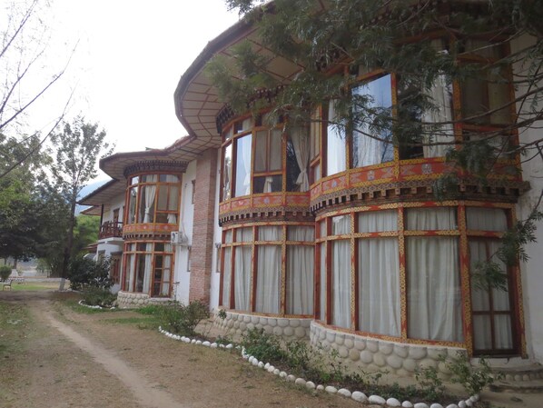 A traditional building with multiple windows, a balcony, and a stone pathway leading to the entrance. - Damchen Resort (Punakha)