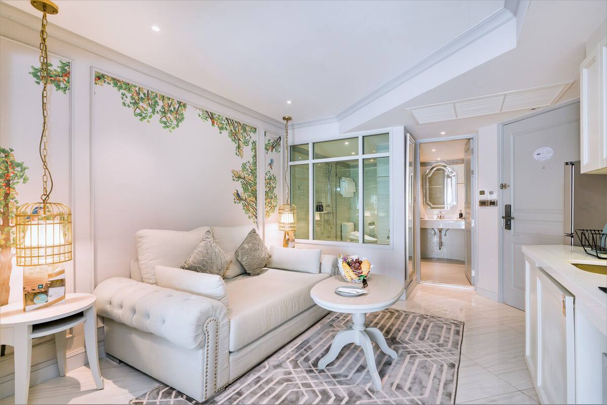 A modern living room with a sofa, a small round table, and a decorative wall with hanging vines.