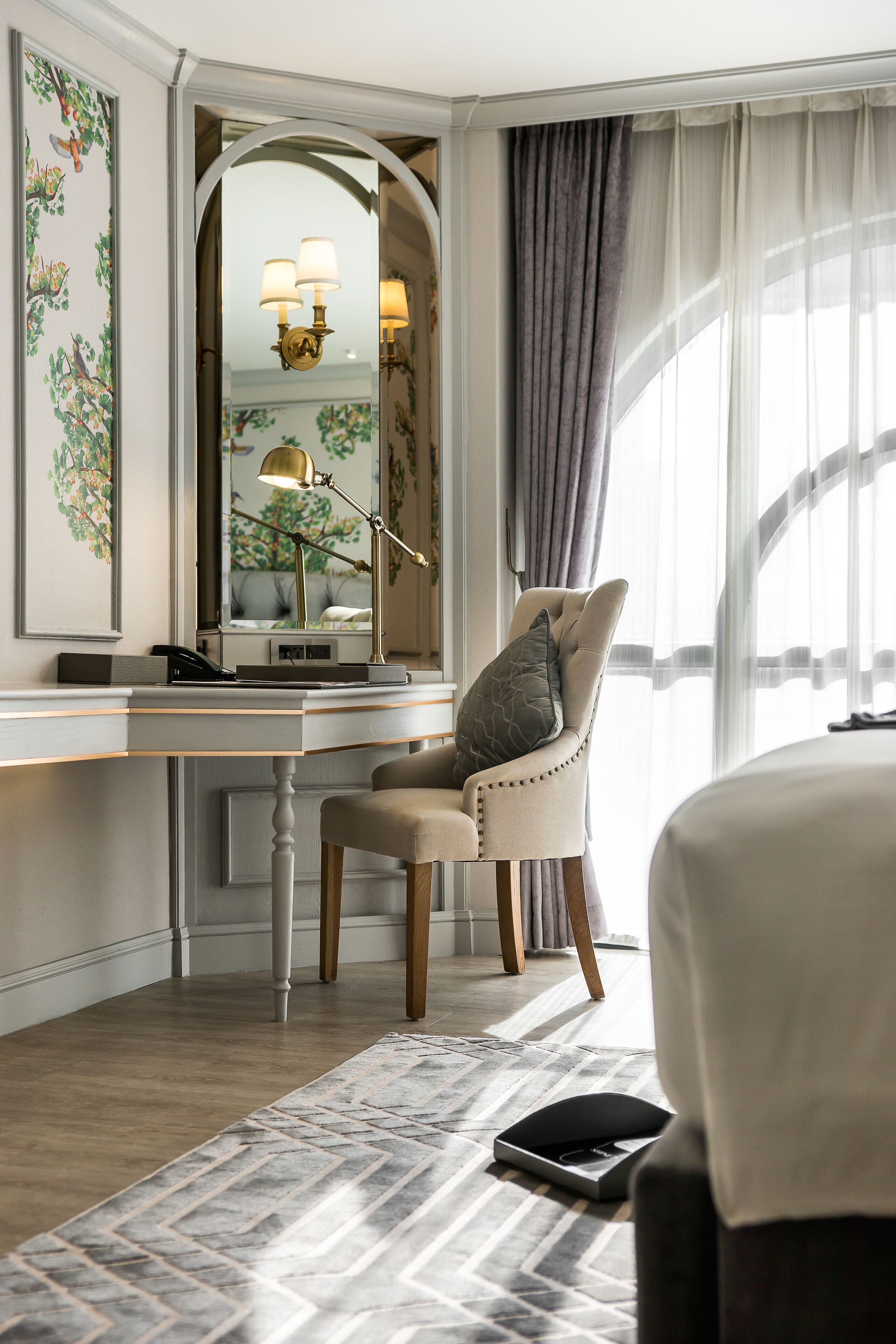 Une chambre d’hôtel équipée d’un bureau, d’une chaise, d’un lit et d’une grande fenêtre avec des rideaux.