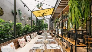 An outdoor dining area with wooden tables and benches, surrounded by greenery and plants. - The Salil Sukhumvit 57 - Thonglor (Bangkok)