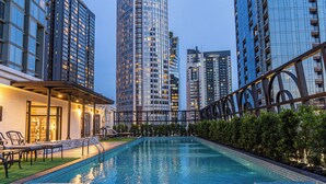 A swimming pool with a tiled edge, surrounded by greenery and modern buildings. - The Salil Sukhumvit 57 - Thonglor (Bangkok)
