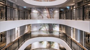 Ein mehrgeschossiges Atrium mit geschwungenen Balkonen, einem offenen Innenhof und einem Chandelier.