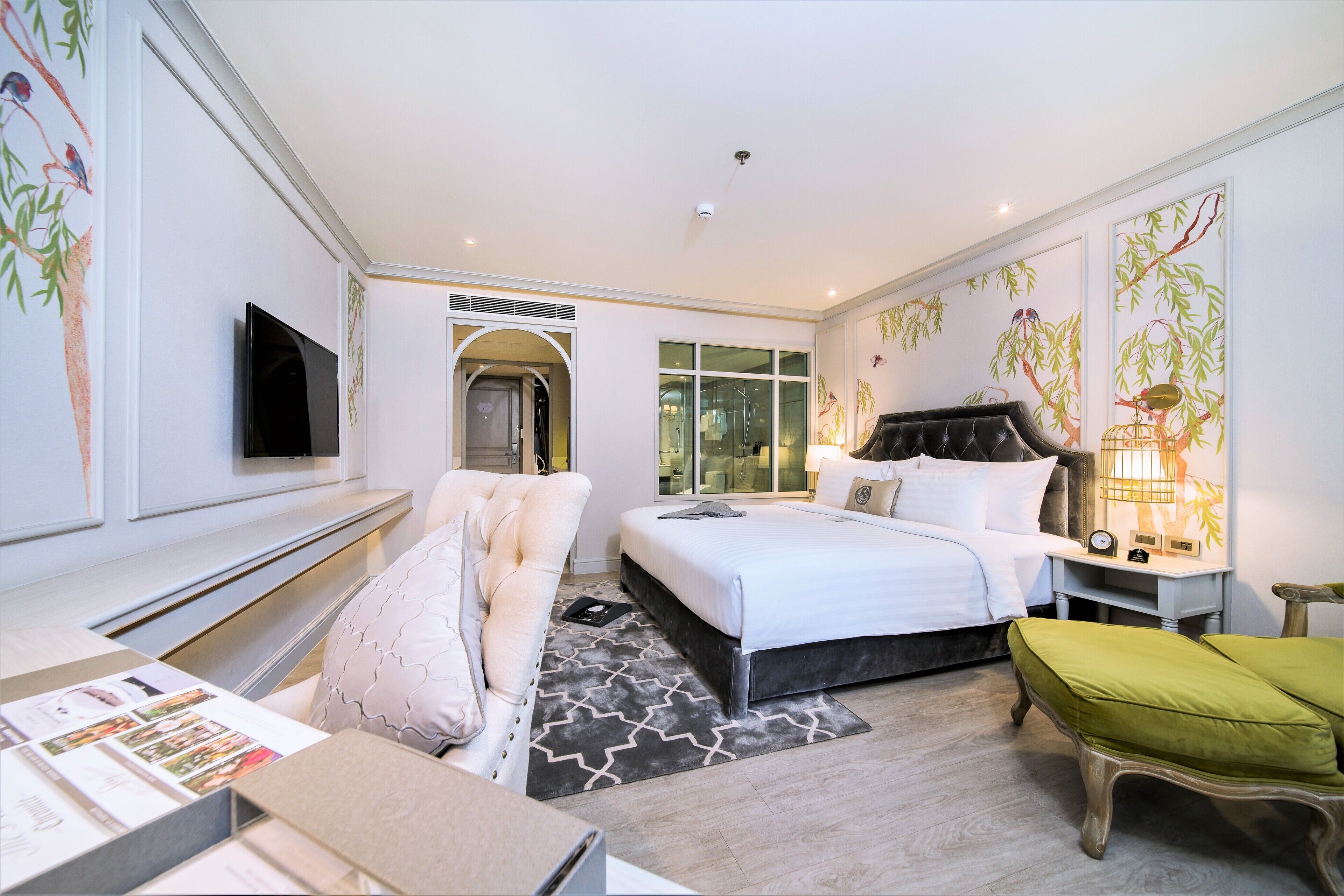 A modern hotel room with a bed, a seating area, a television, and artwork on the walls.