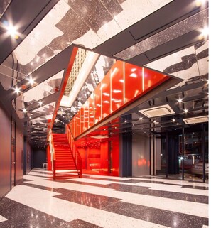 A modern interior with a prominent red staircase and geometric ceiling design. - Klub Hotel (Bangkok)