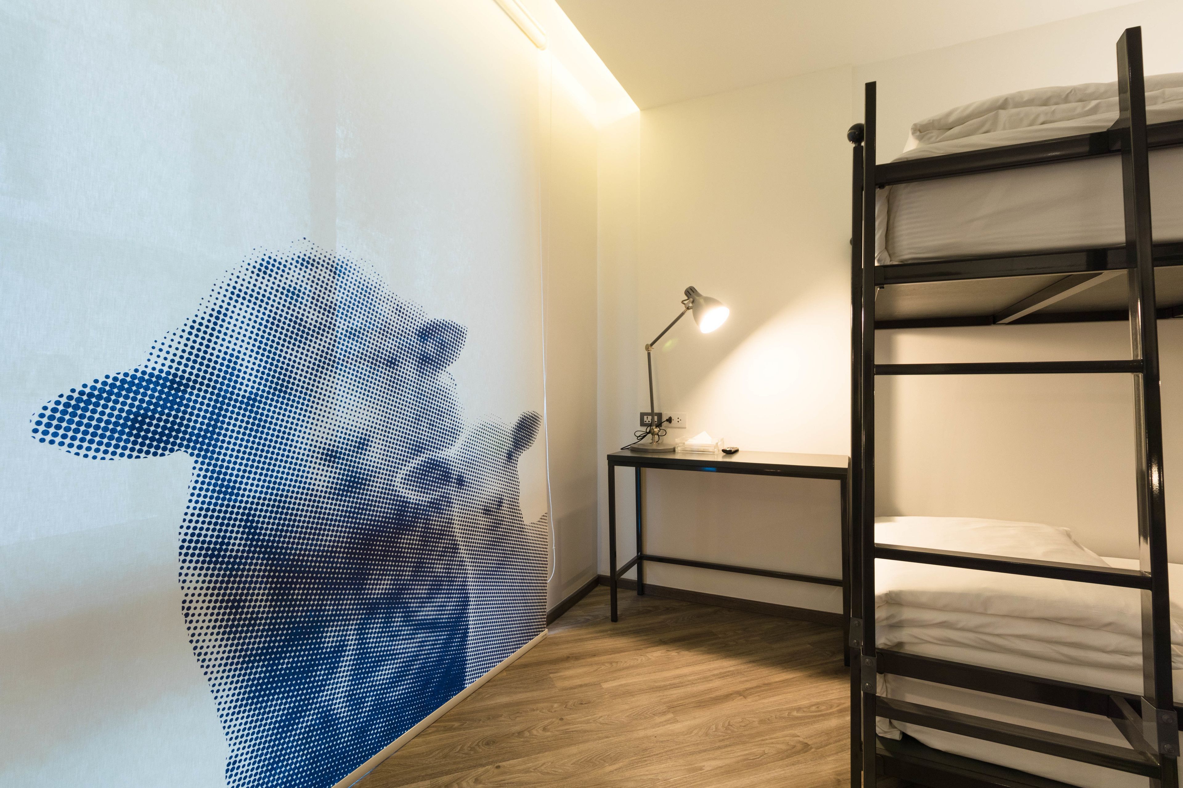 A room with a bunk bed, a desk with a lamp, and a wall with a blue dot pattern.