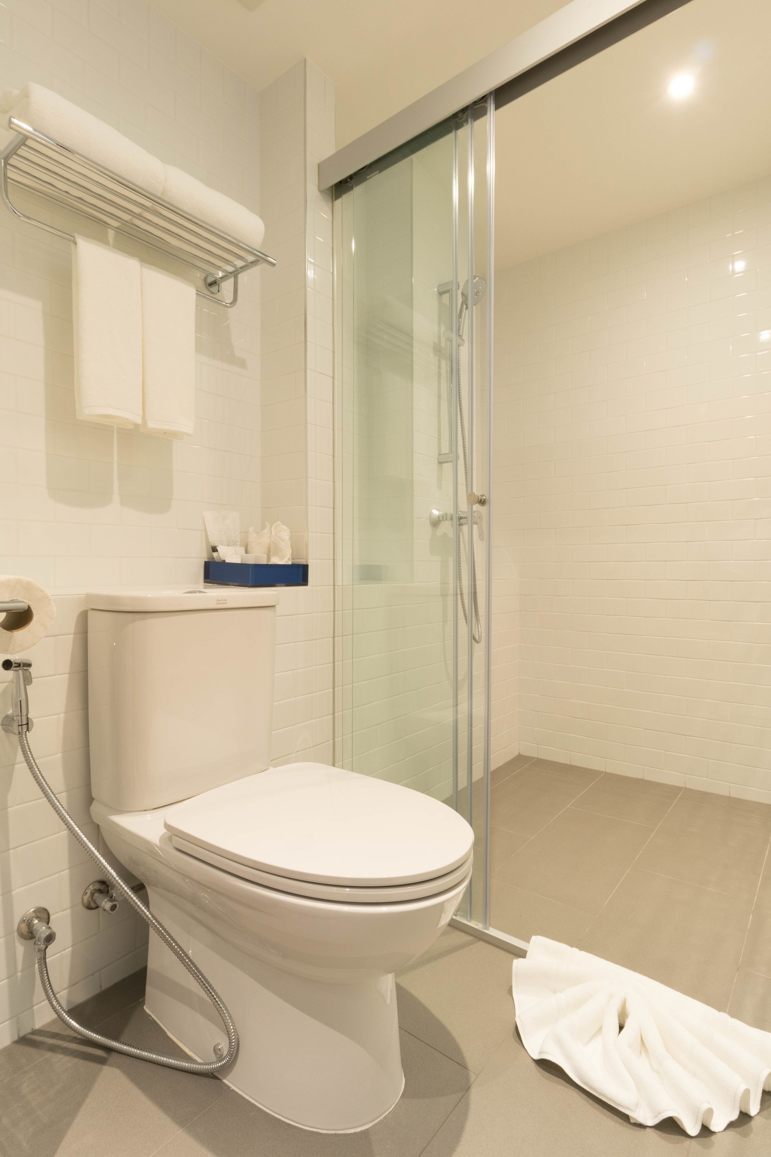 Une salle de bain moderne équipée de toilettes, d’une douche et d’un espace douche clos par des parois de verre.