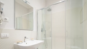 Een moderne badkamer met een witte wastafel, een douchecabine van glas en een grote spiegel.
