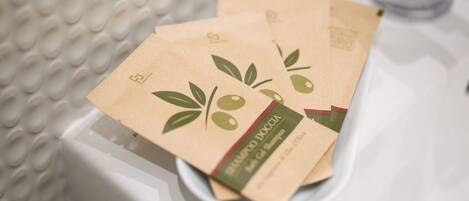 A white sink with three brown paper bags with green leaf and olive designs.