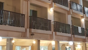 A multi-story hotel with balconies, outdoor seating, and a pool area. - Charming Inn Hotel (Pattaya)