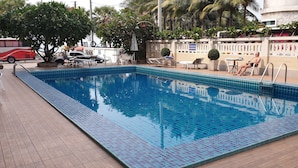 A rectangular pool with blue tiles, surrounded by lounge chairs and a tiled deck. - Charming Inn Hotel (Pattaya)