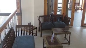 Una habitación con muebles de madera, un cartel anunciando meditación y yoga, y vistas a través de una ventana.