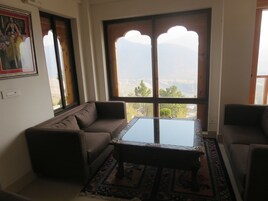 Sala de estar com sofá, mesa de centro e vista pela janela.