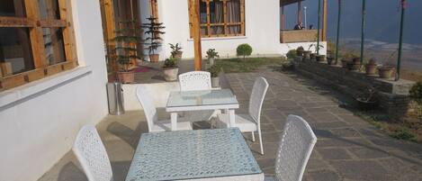 A patio area with a table and chairs, potted plants, and a view of the landscape.