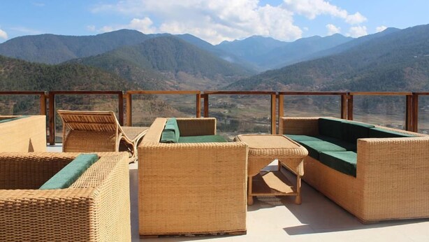 Una terraza con mobiliario de mimbre y vistas a montañas.