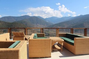 Terraço com mobiliário de vime e vista para montanhas.