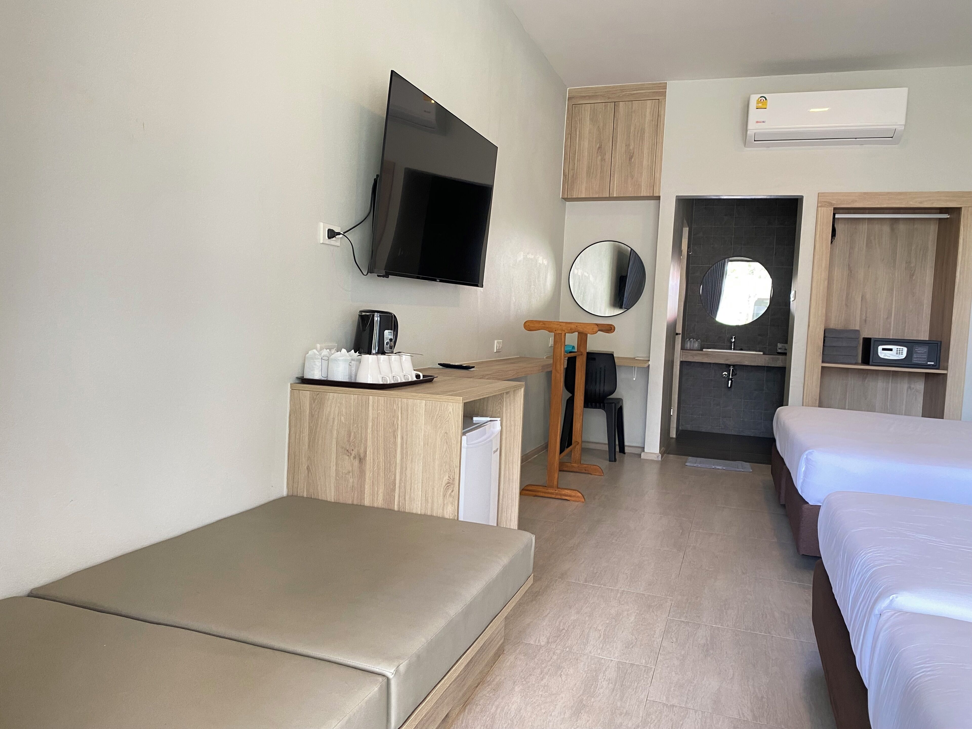 Une chambre d’hôtel comprenant un lit, un bureau avec une machine à café, une télévision, un miroir et une armoire.
