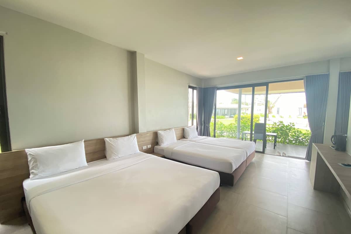 Habitación de hotel con dos camas, un escritorio y vistas al exterior.