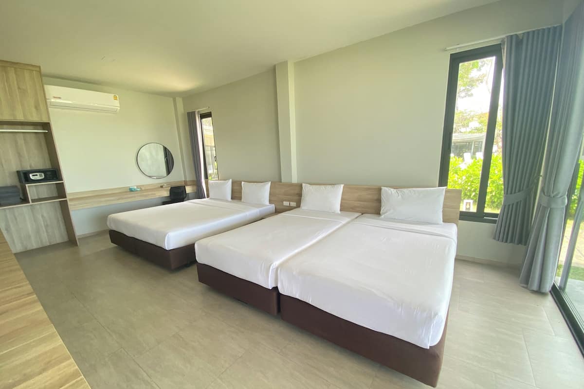 Habitación de hotel con dos camas, un escritorio, una silla, un espejo y una ventana con cortinas.