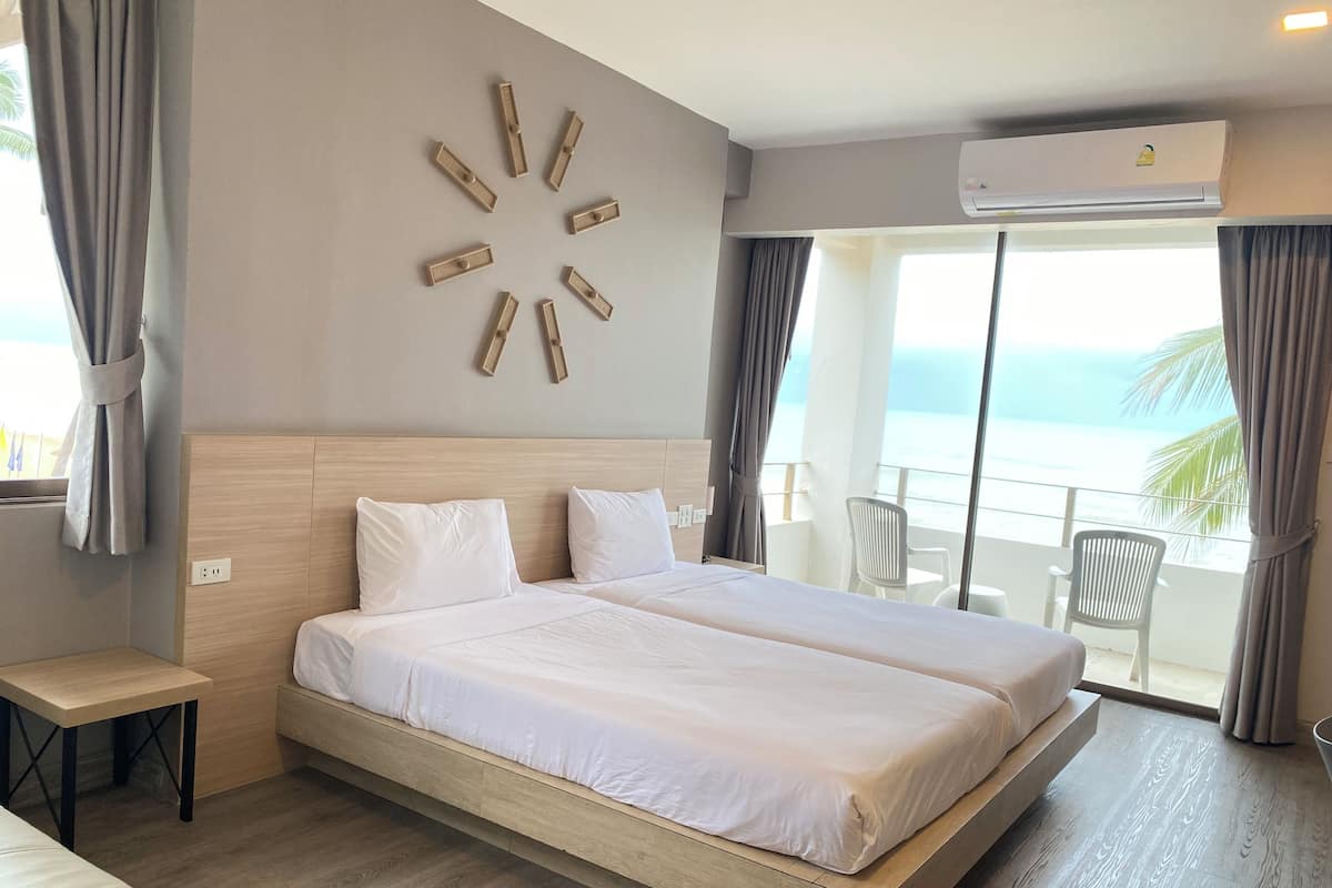 Una habitación de hotel con una cama grande, una mesita y vista al océano.