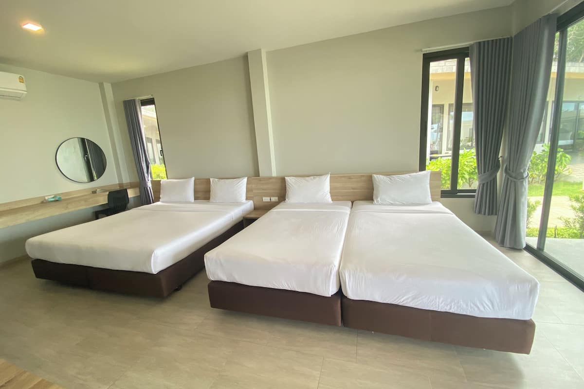 Habitación de hotel con dos camas grandes, un espejo redondo y una ventana con cortinas.