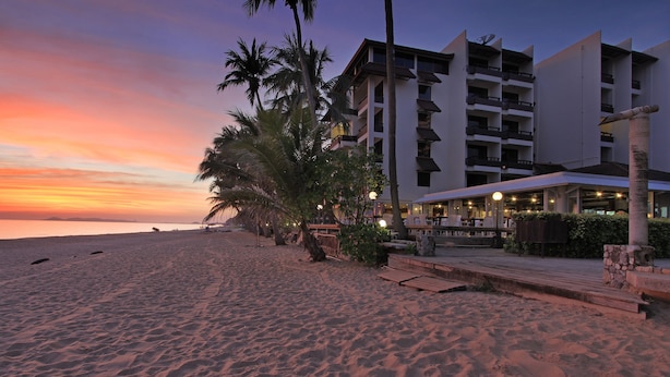 A beachfront hotel with a pool area, palm trees, and a sunset view. - Rayong Chalet Resort (Klaeng)