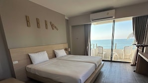 A hotel room with two beds, a balcony with a view of the sea, and a seating area with chairs. - Rayong Chalet Resort (Klaeng)
