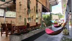 A restaurant with bamboo walls, wooden furniture, and hanging plants. - Samui Zenity Hotel (Koh Samui)