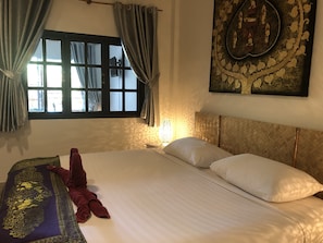 A bedroom with a bed, curtains, a wall-mounted lamp, and a decorative wall piece. - Samui Zenity Hotel (Koh Samui)